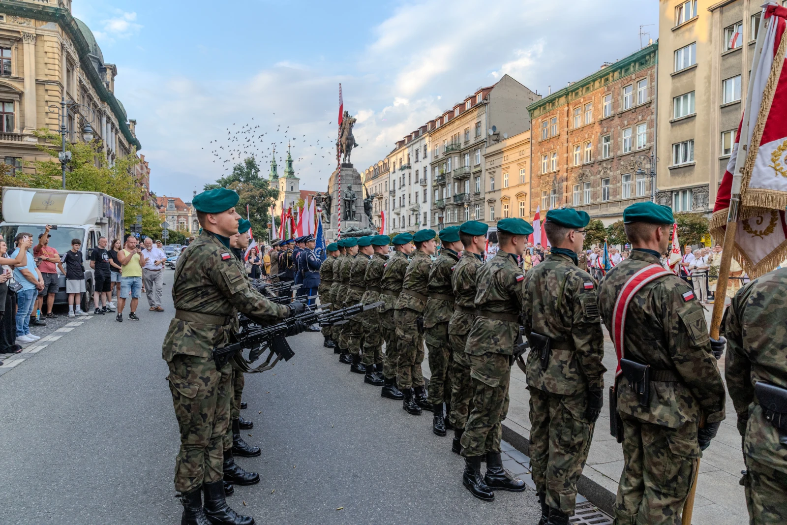 Żołnierze w mundurach z bronią, obok pomnika, podczas uroczystości z flagami. Autor: Bogusław Świerzowski