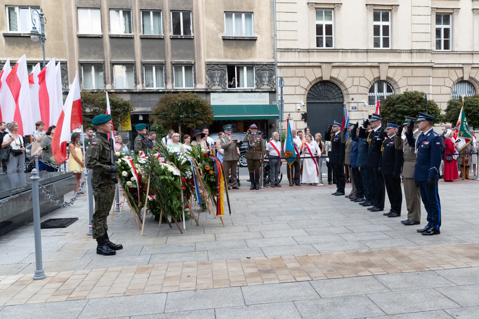 Uroczystość złożenia kwiatów przez żołnierzy i przedstawicieli władz w towarzystwie flag narodowych. Autor: Bogusław Świerzowski
