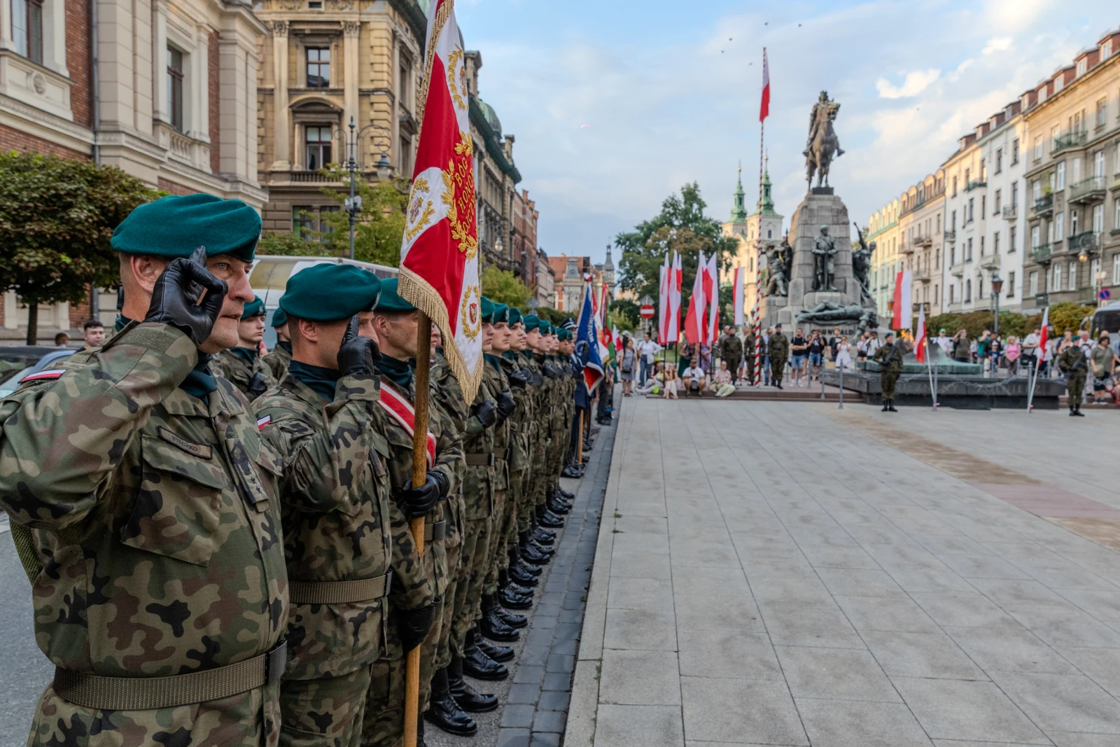 Żołnierze w mundurach salutują podczas uroczystości na placu z pomnikiem. Autor: Bogusław Świerzowski