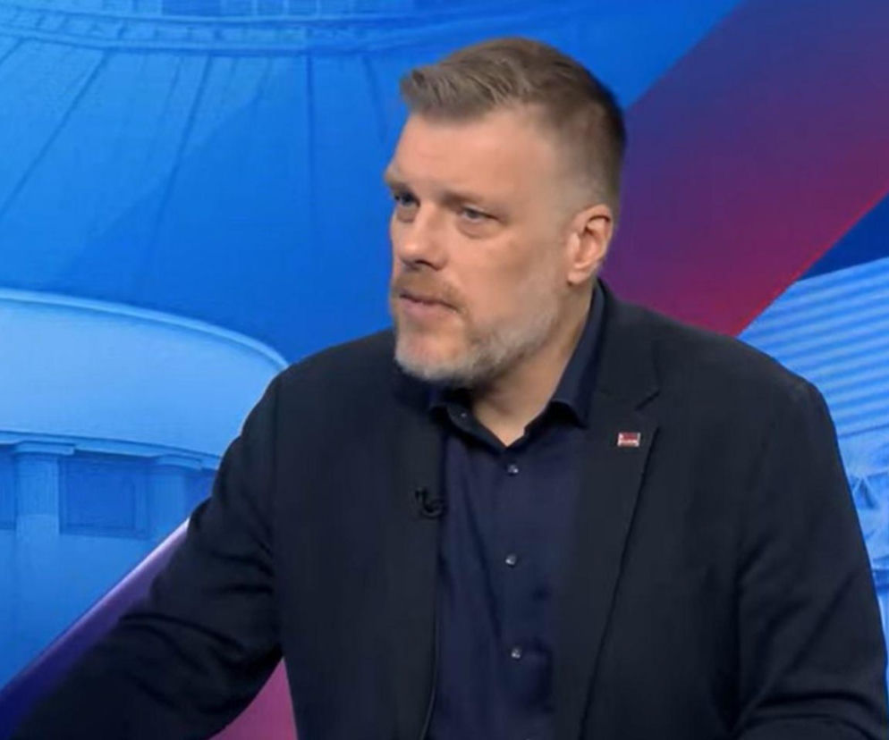 Adrian Zandberg w granatowej marynarce podczas wywiadu. O jego krytyce ochrony zdrowia przeczytasz na VOX FM.