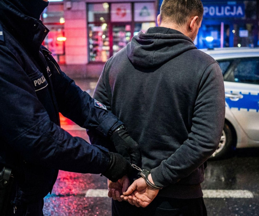 Policjant zakłada kajdanki mężczyźnie w ciemnej bluzie. O areszcie w Szczytnie przeczytasz na Eska Olsztyn.