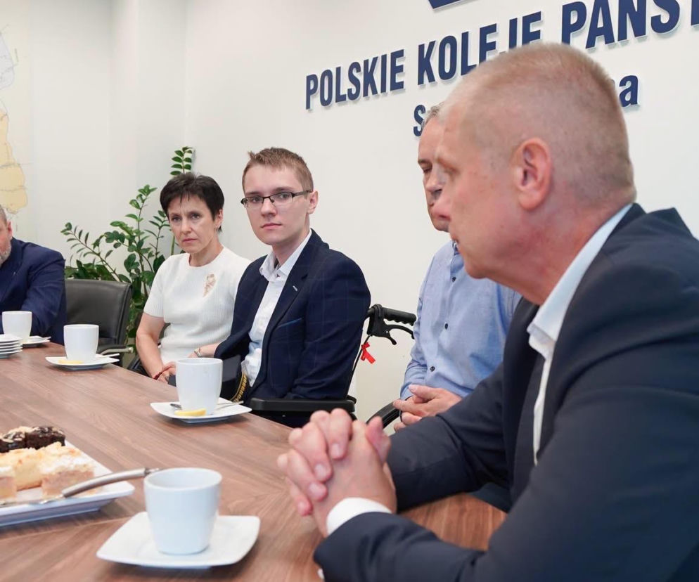 Dominik Hołuj siedzi przy stole w centrali PKP. O wsparciu dla nastolatka po wypadku przeczytasz na Eska Radom.