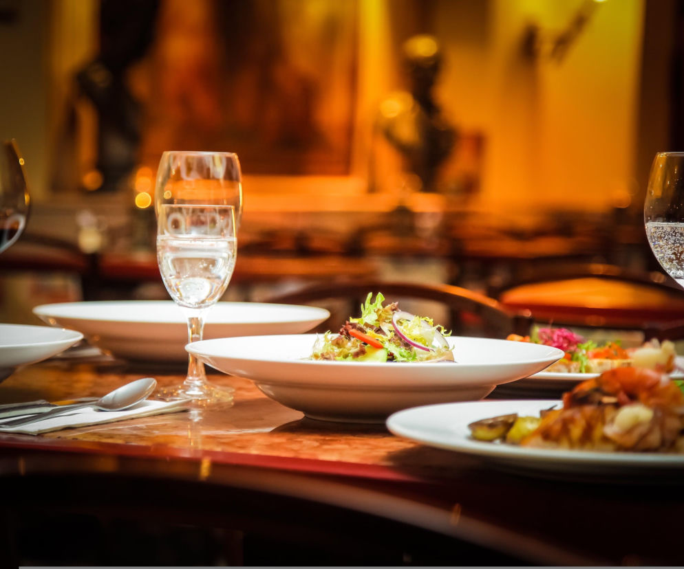Dania i kieliszki z trunkami na stole w eleganckiej restauracji. O oszuście z Lęborka przeczytasz na Eska Trójmiasto.