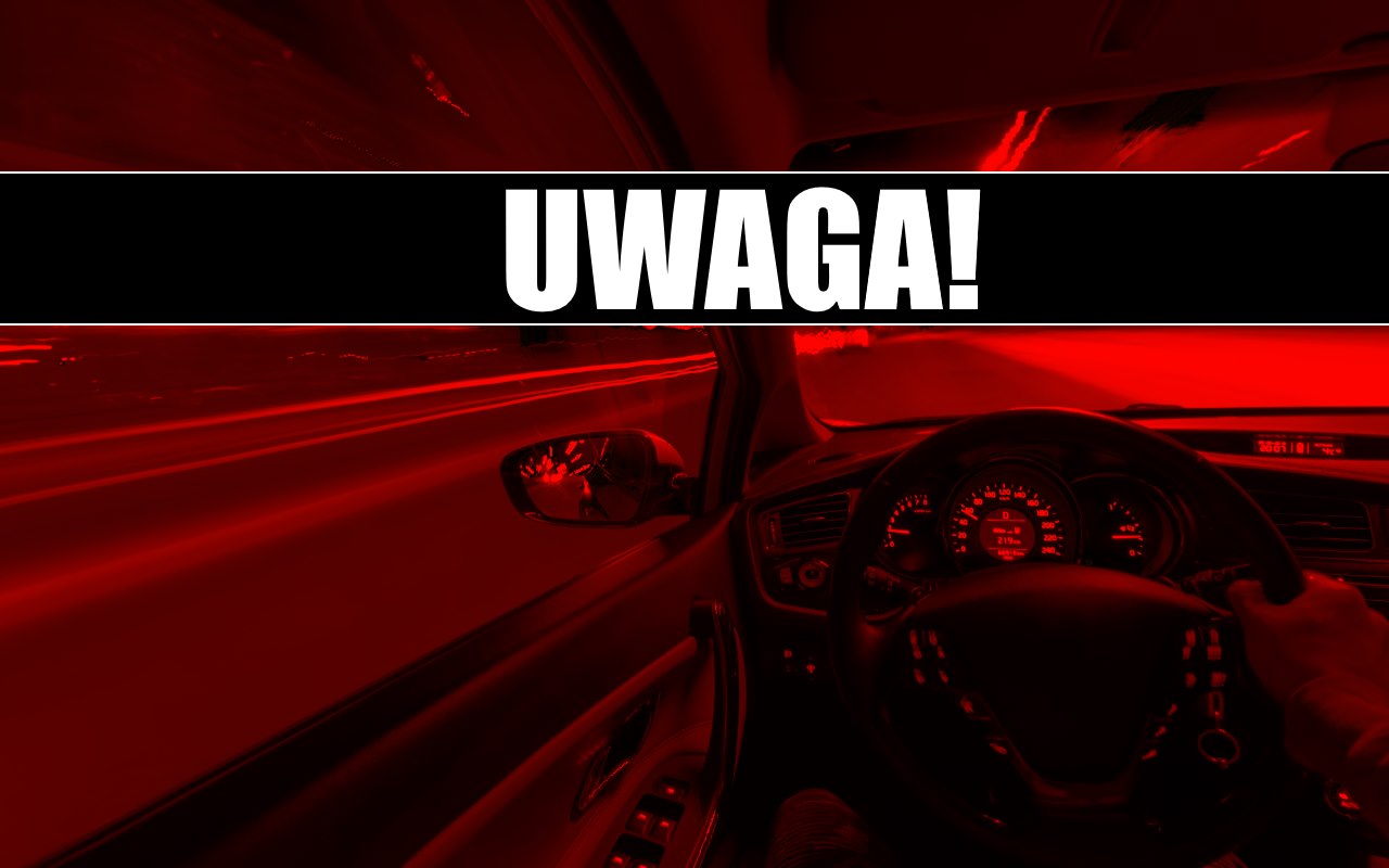 Samochód jedzie po drodze. Widok z wnętrza auta. Na pasku napis "Uwaga".