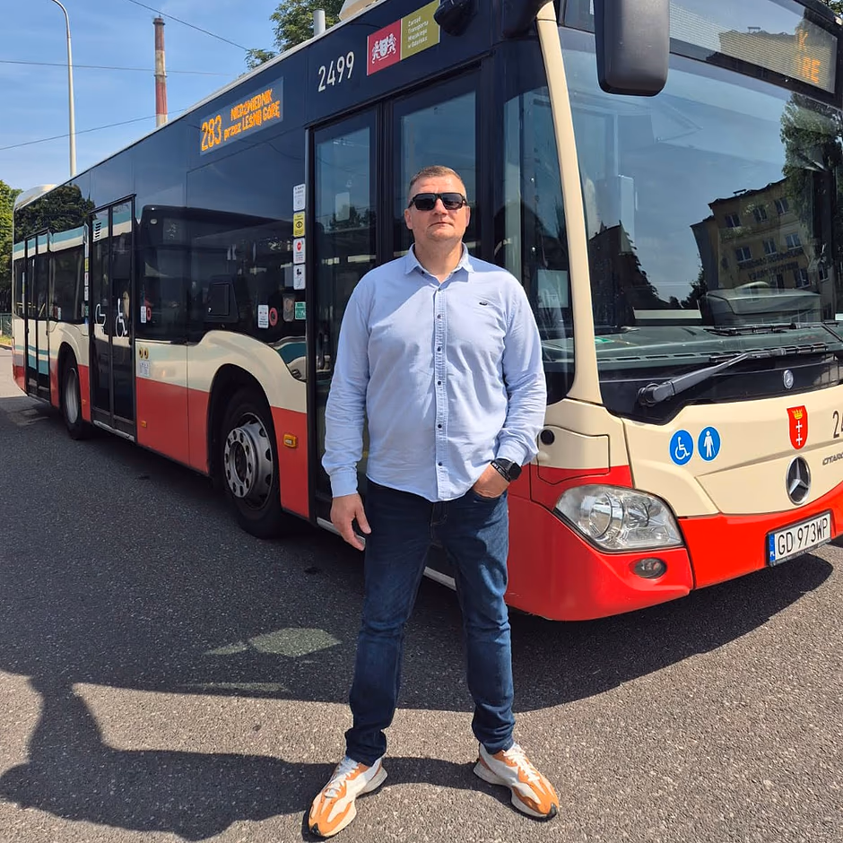 Zdjęcie mężczyzny, który pozuje do zdjęcia na tle autobusu miejskiego