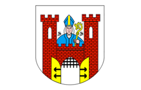 na herbie brama zamkowa żółta, czerwone mury, na zamku postać duchownego