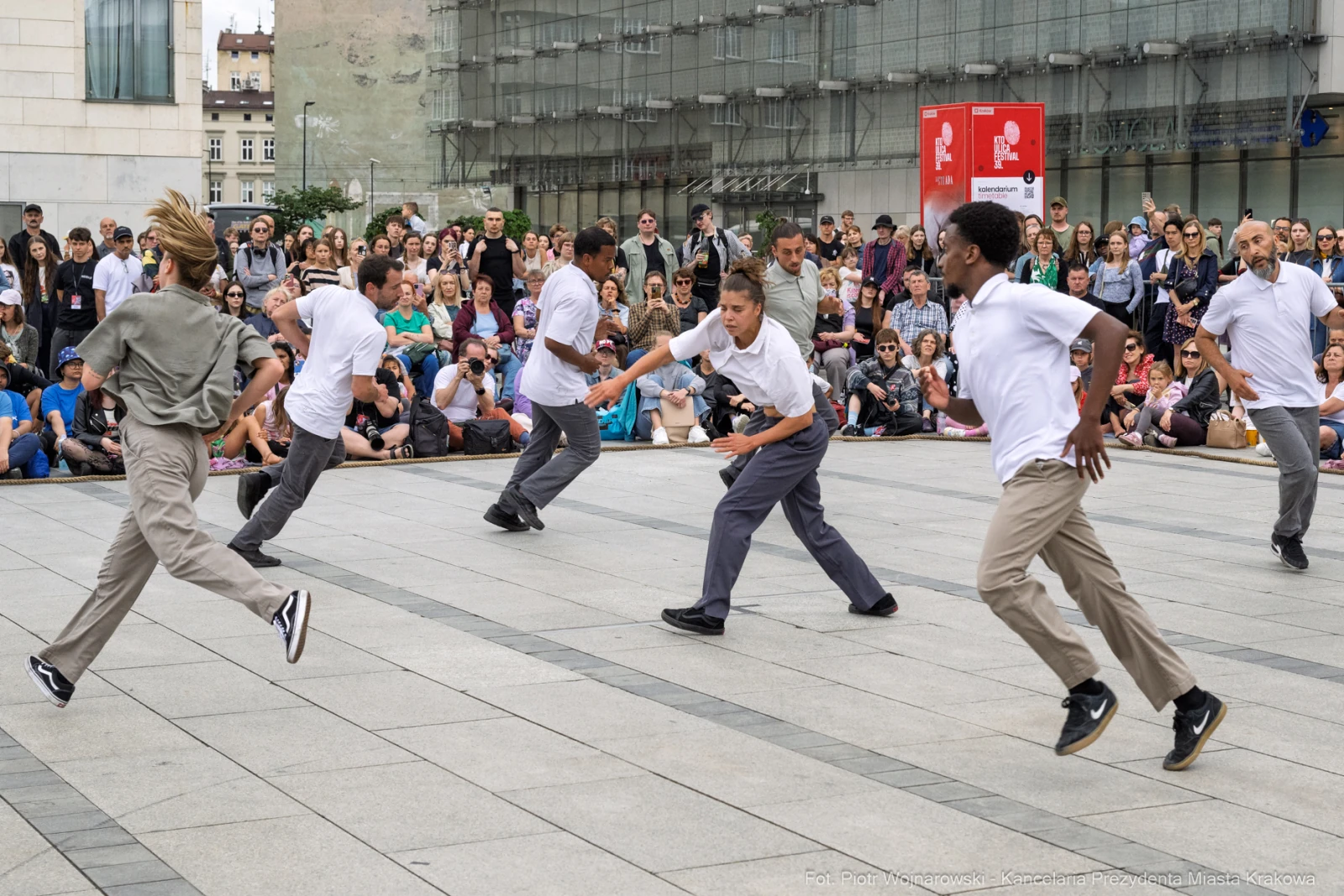 Grupa tancerzy wykonujących choreografię na placu, otoczona widownią. Autor: Piotr Wojnarowski