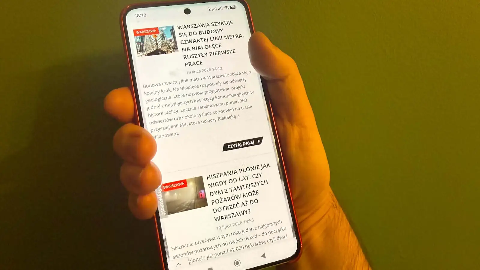 Smartfon na ekranie którego widać stronę główną serwisu Warszawa w Pigułce.