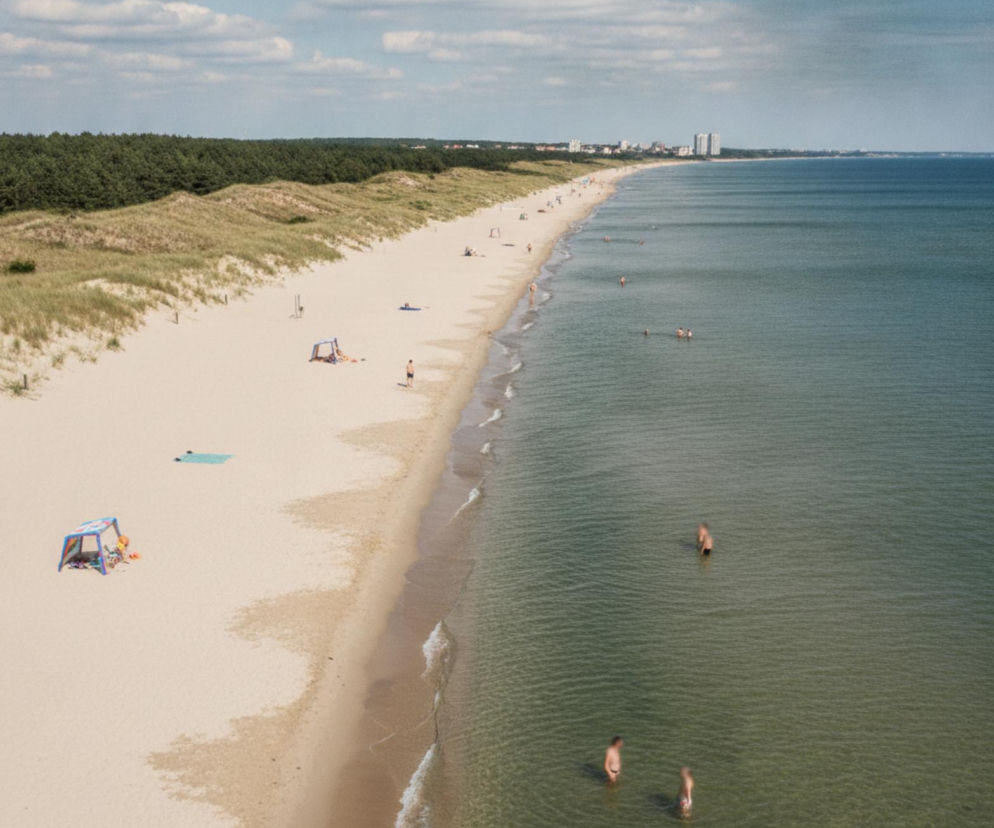 Szeroka, piaszczysta plaża nad Bałtykiem z nielicznymi ludźmi. O liście kąpielisk na Pomorzu przeczytasz na Demo.