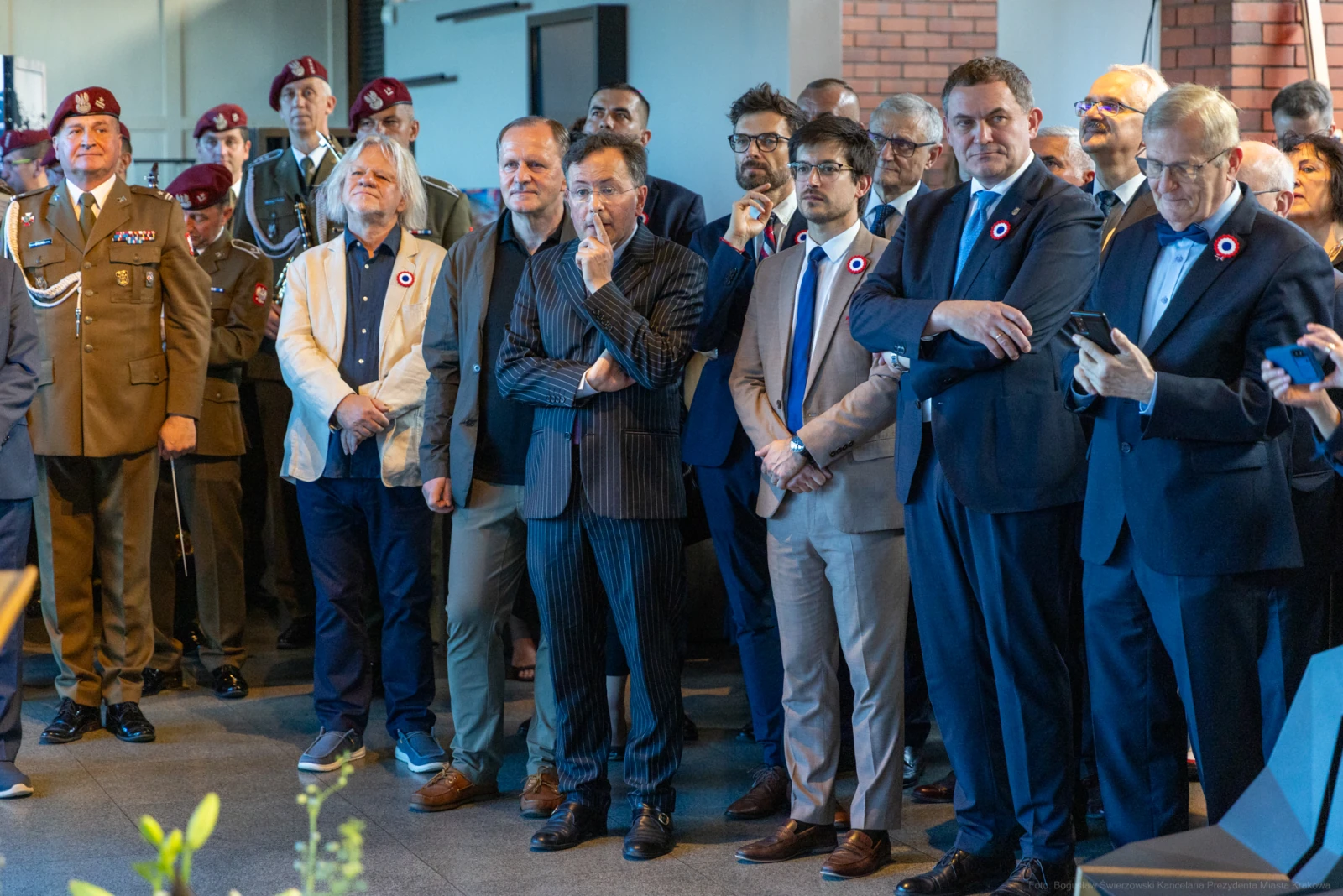 Grupa mężczyzn w garniturach i mundurach, z zainteresowaniem obserwujących wydarzenie. Autor: Bogusław Świerzowski