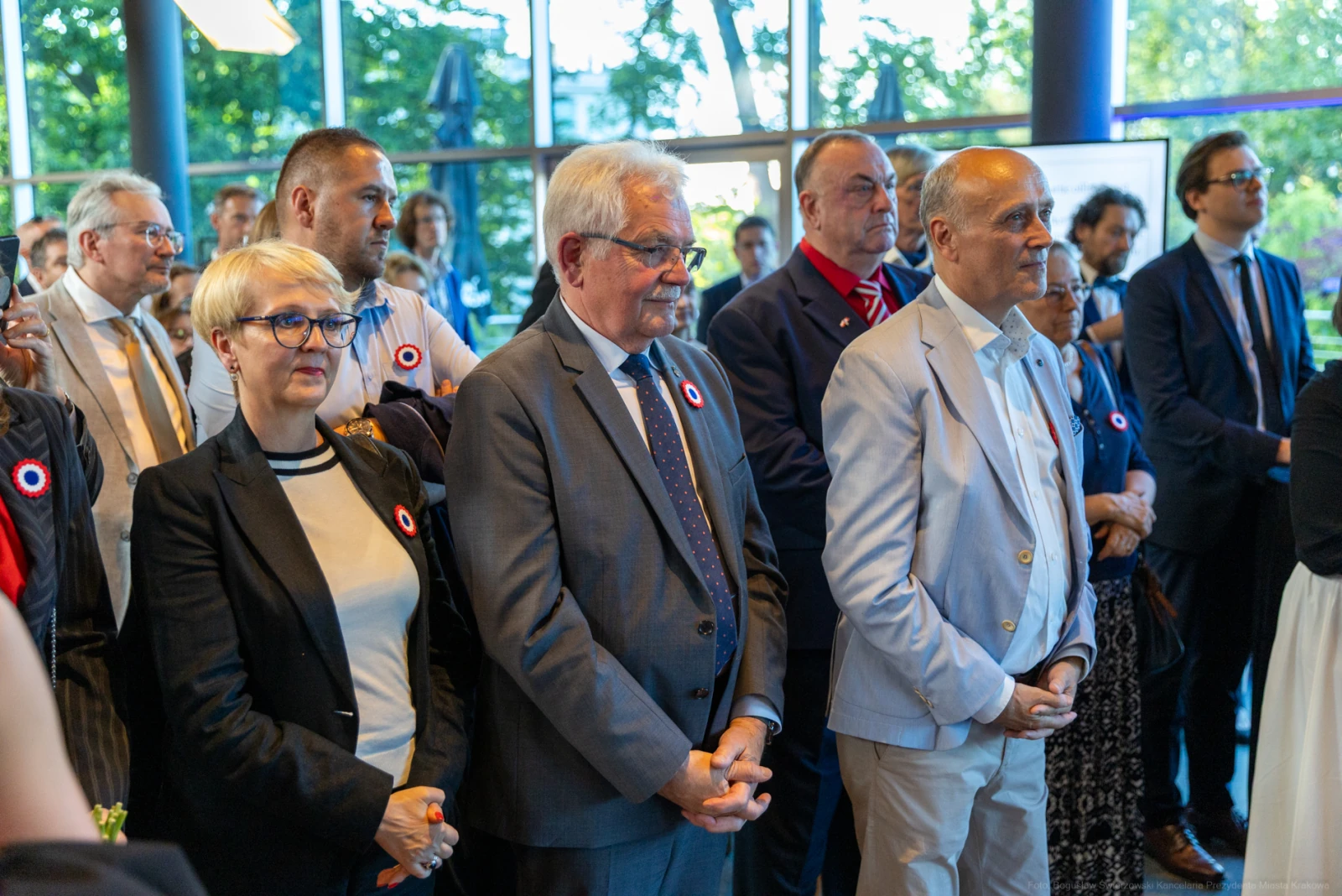 Grupa ludzi w eleganckich strojach, z przypinkami, uczestniczy w wydarzeniu. Autor: Bogusław Świerzowski