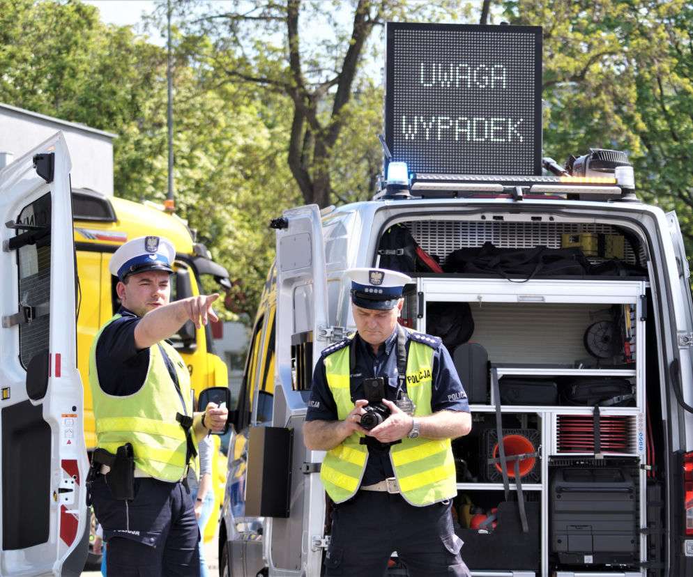 Policjanci przy radiowozie z napisem Uwaga Wypadek. O tragedii w Dzielicach przeczytasz na Eska Poznań.