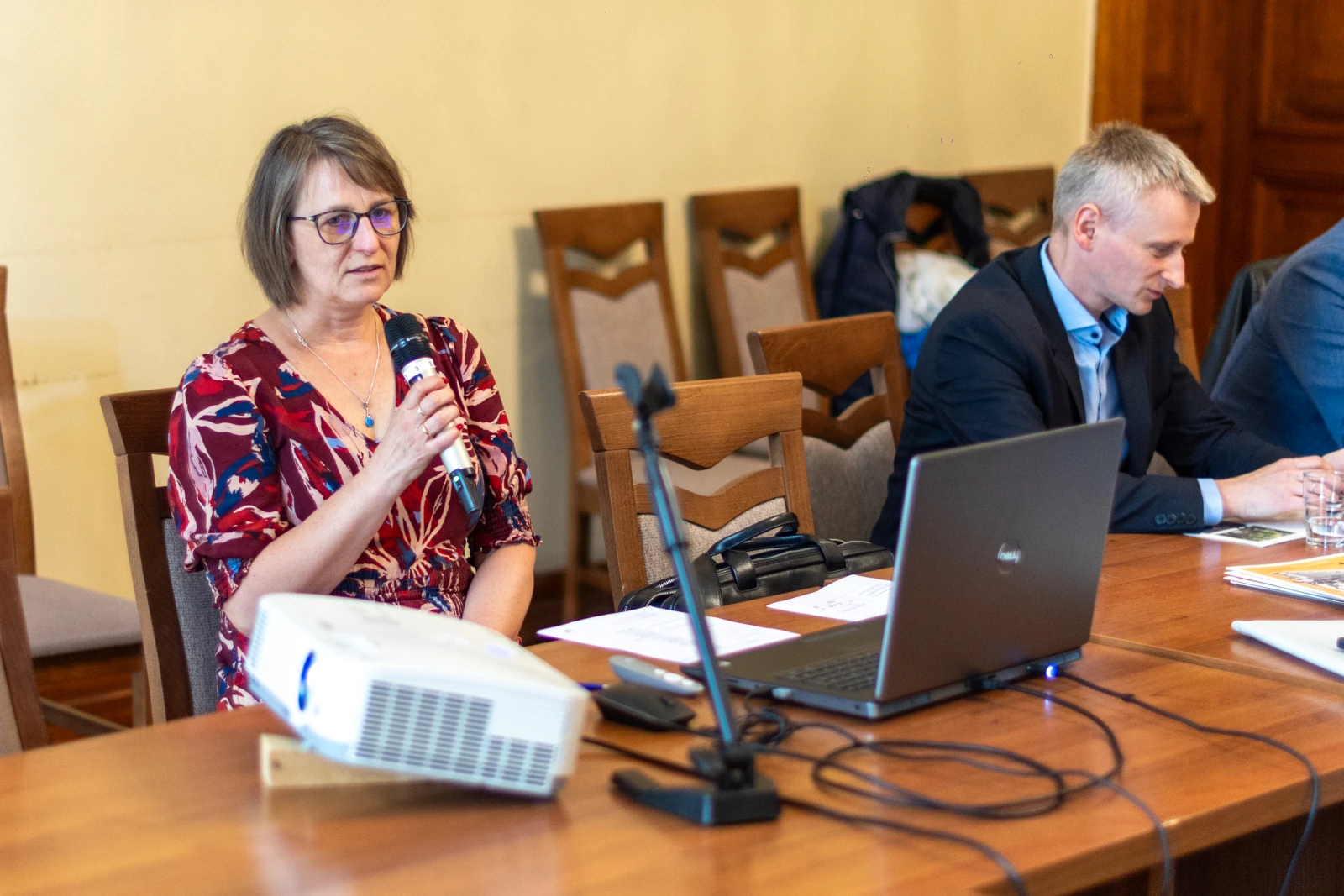 Kobieta z mikrofonem przemawia podczas spotkania, obok mężczyzna przy laptopie. Autor: Bogusław Świerzowski