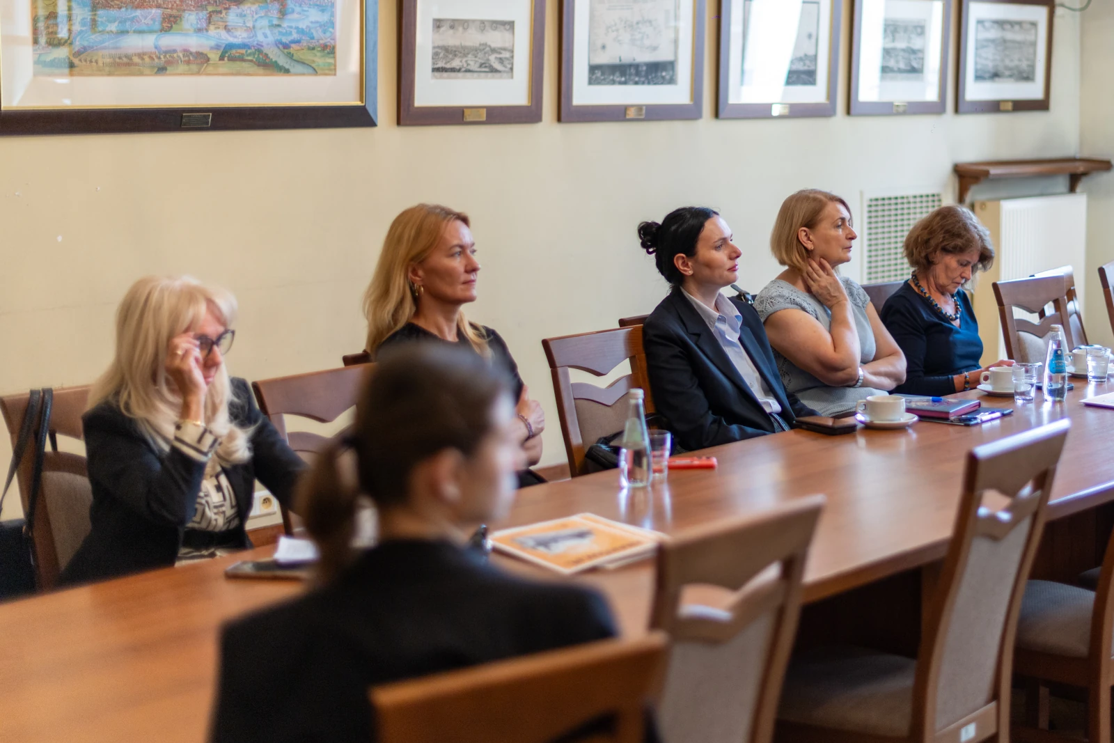 Grupa kobiet w formalnych strojach siedzi przy stole w sali konferencyjnej. Autor: Bogusław Świerzowski
