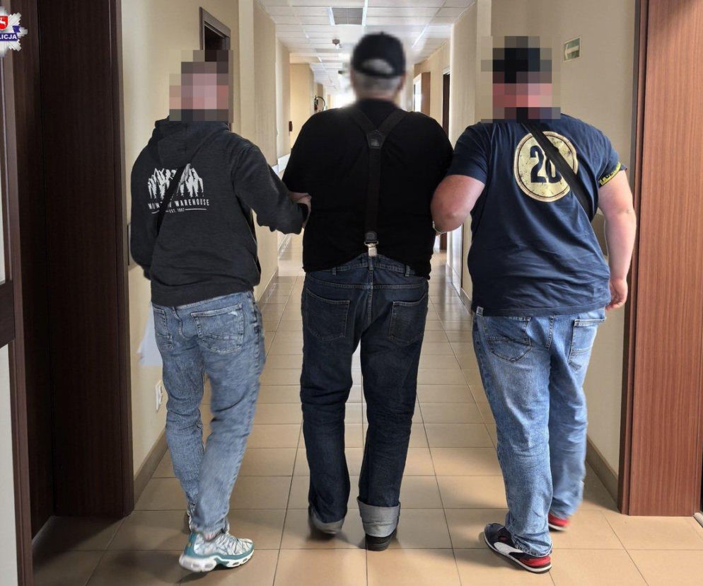 Dwaj policjanci prowadzą korytarzem zatrzymanego 67-latka z Lublina. O kradzieży czekolad przeczytasz na Eska Lublin.