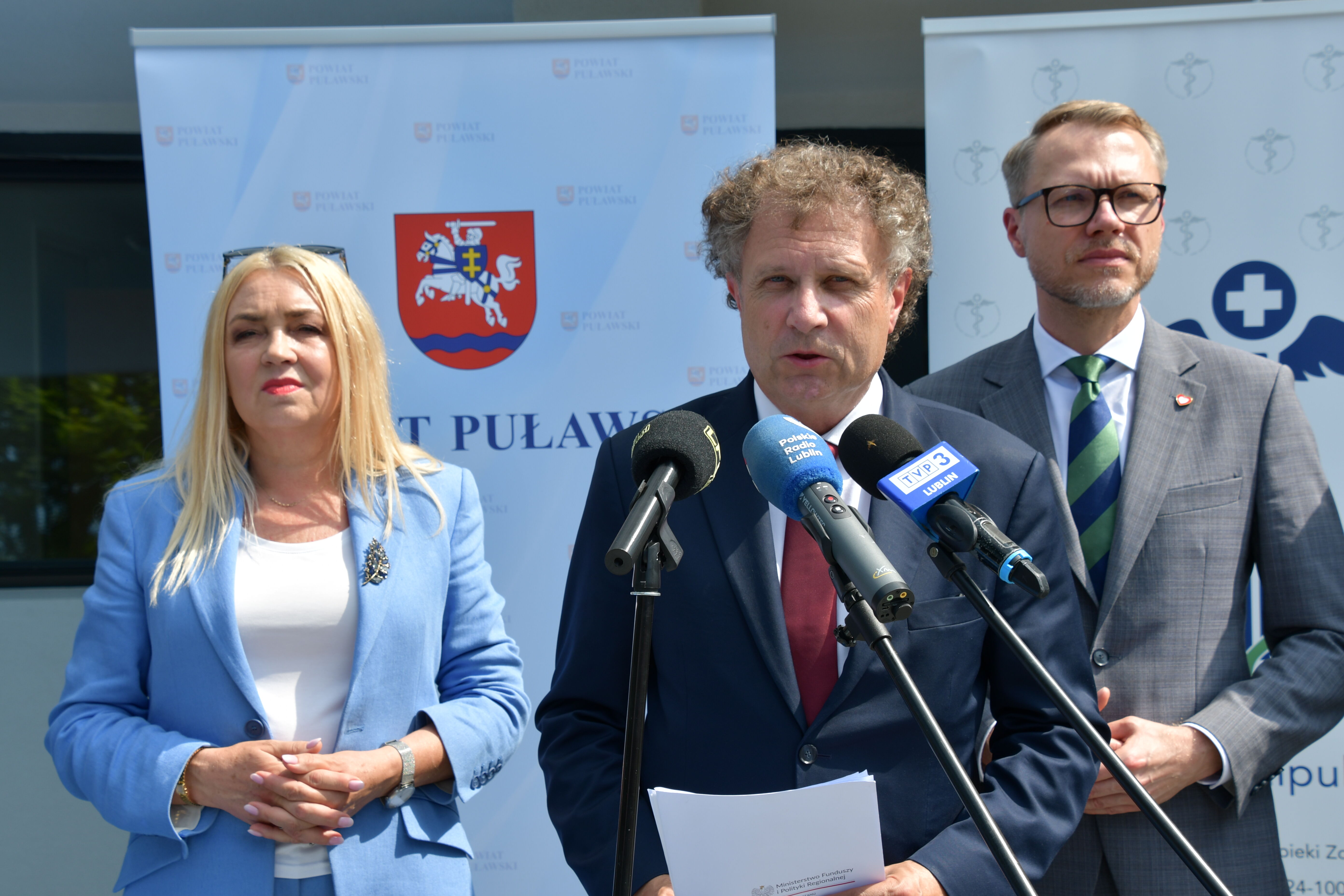 Konferencja prasowa, w tle rollupy reklamowe