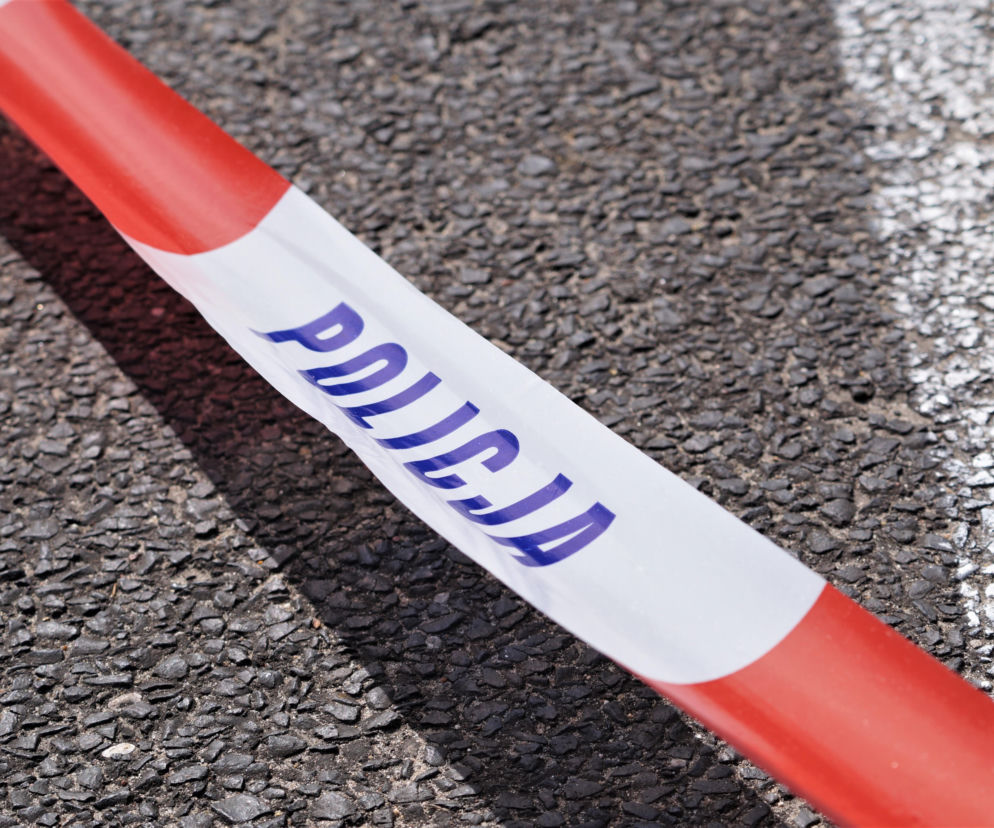 Biało-czerwona taśma policyjna z napisem POLICJA na asfalcie. O tragedii w Otominie przeczytasz na Eska Trójmiasto.
