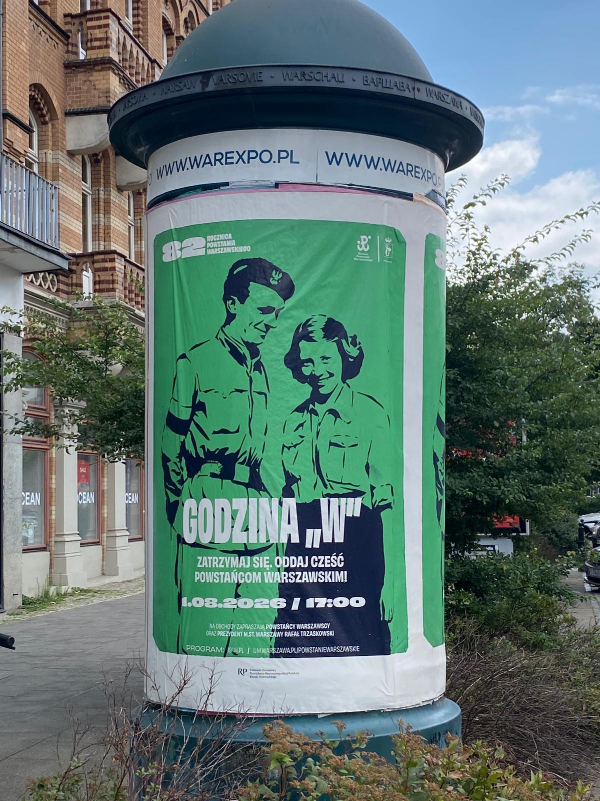 Okrągły słup ogłoszeniowy z grafiką dot. uroczystości upamiętniających wybuch Powstania Warszawskiego