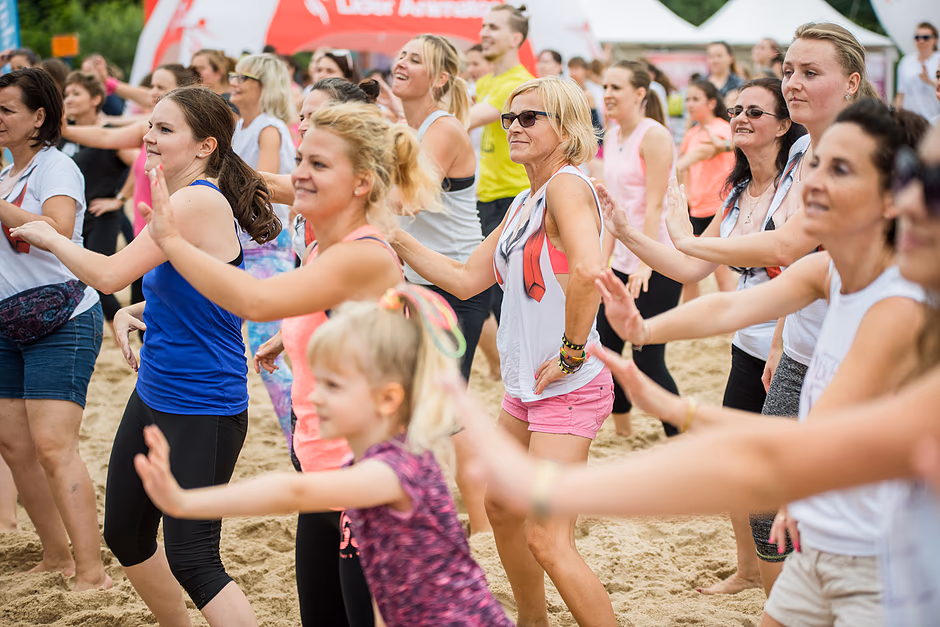 Ludzie (głównie kobiety) ćwiczą zumbę na plaży