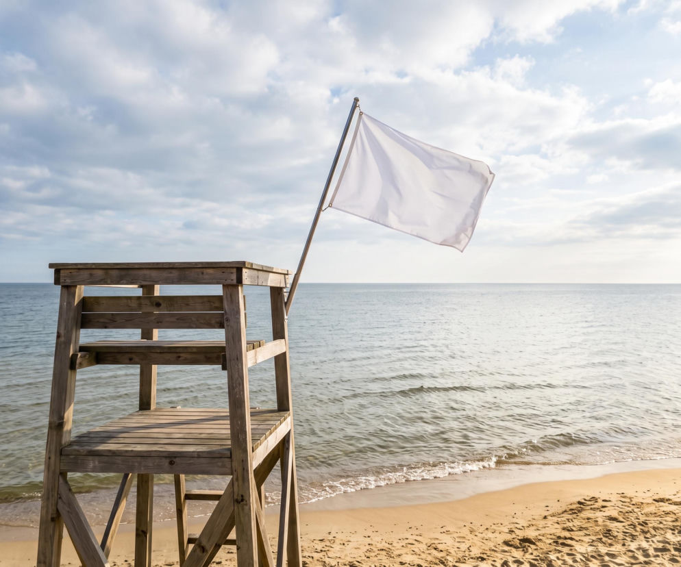 Biała flaga na wieży ratowniczej przy pustej plaży. O bezpiecznej kąpieli w Chałupach przeczytasz na Eska Trójmiasto.