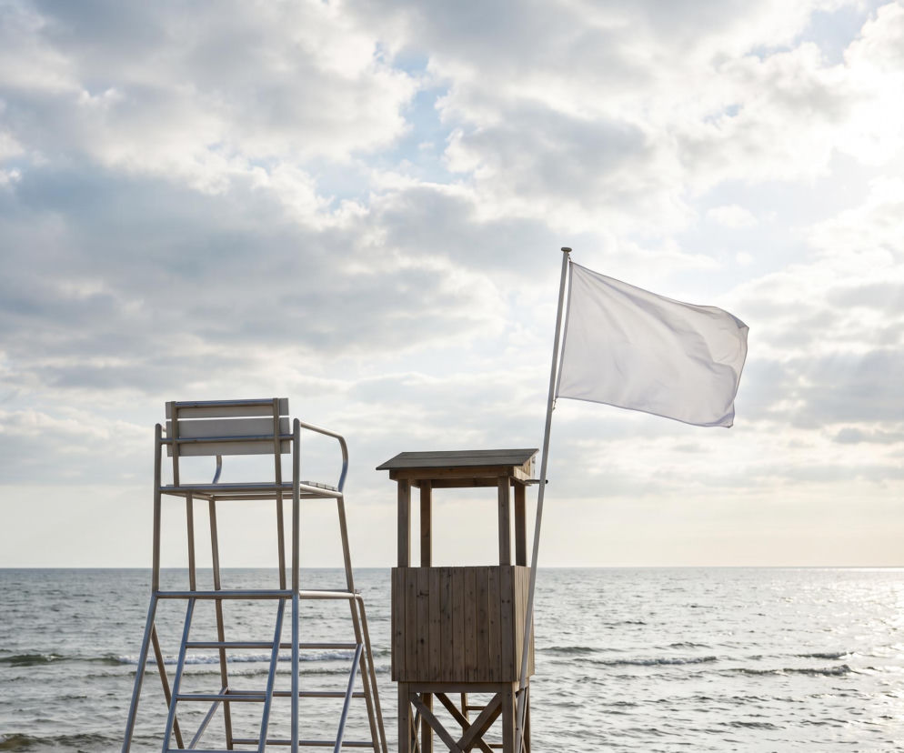 Biała flaga i wieża ratownicza na plaży w Chałupach. O bezpiecznej kąpieli przeczytasz na Eska Trójmiasto.