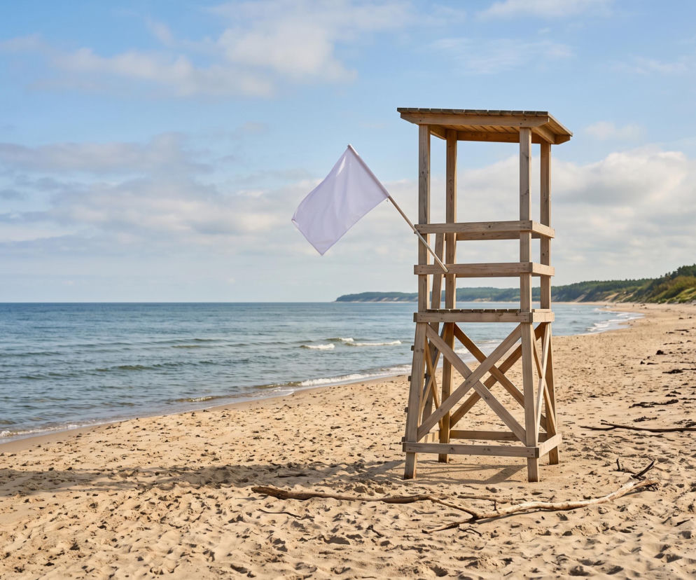 Biała flaga na wieży ratowniczej na pustej plaży. O bezpiecznej kąpieli w Dąbkach przeczytasz na SE Szczecin.