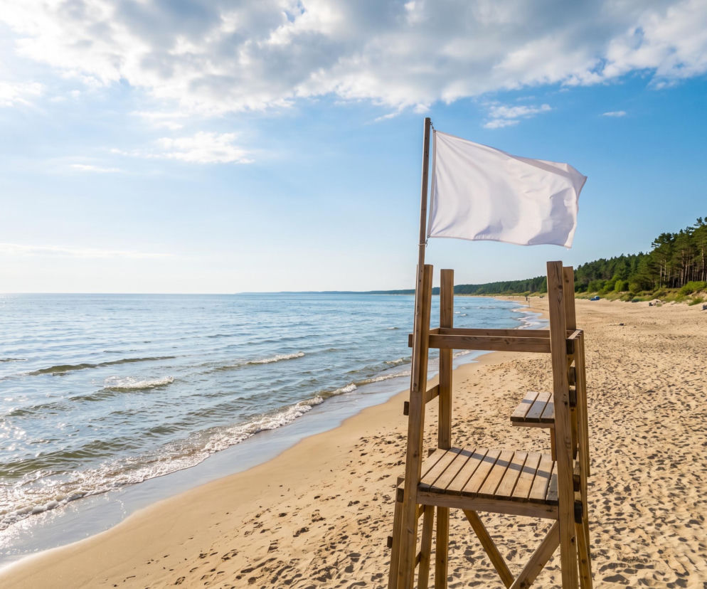Biała flaga na wieży ratowniczej przy pustej plaży w Dziwnowie. O warunkach kąpieli przeczytasz na SE Szczecin.