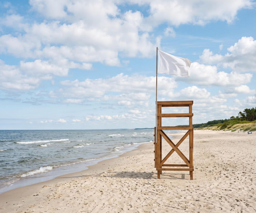 Drewniana wieża ratownika z białą flagą na plaży w Dźwirzynie. O braku sinic przeczytasz na SE Szczecin.