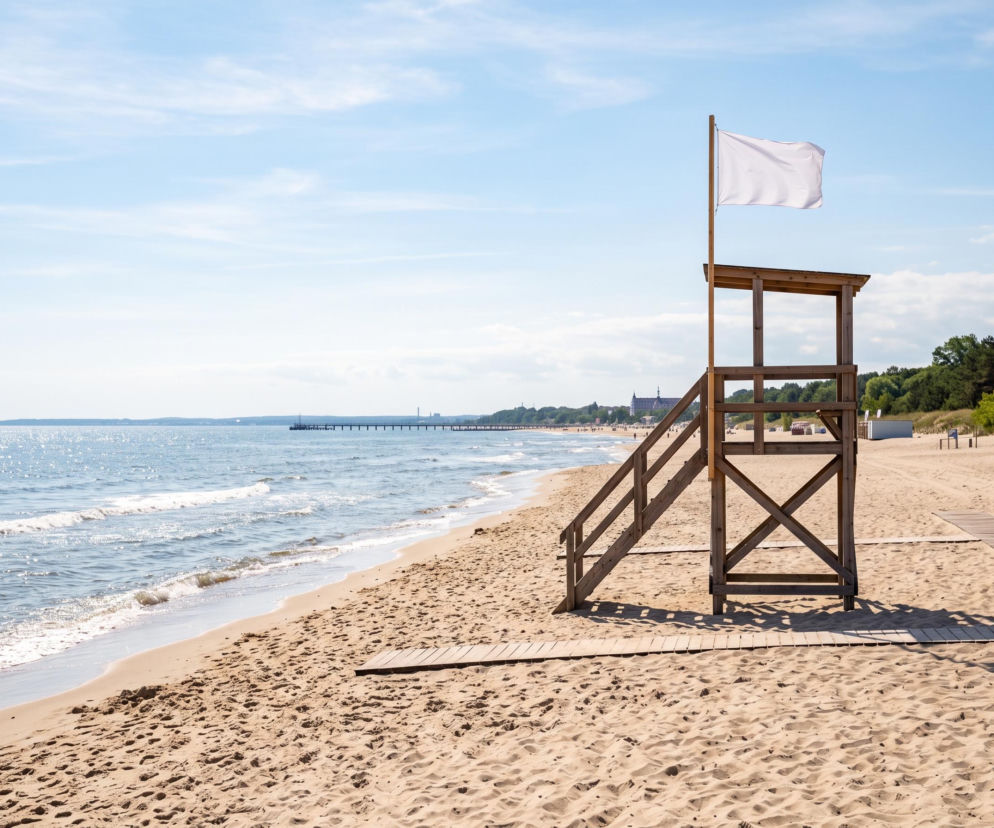 Drewniana wieża ratownika z białą flagą na plaży w Gdańsku. O czystości wody w kąpieliskach przeczytasz na Eska Trójmiasto.