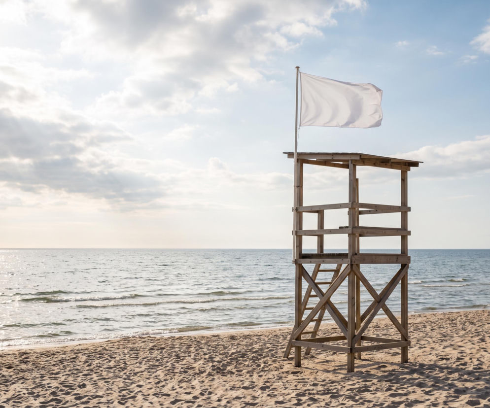 Biała flaga na wieży ratowniczej na pustej plaży w Gdyni. O bezpiecznych kąpielach przeczytasz na Eska Trójmiasto.