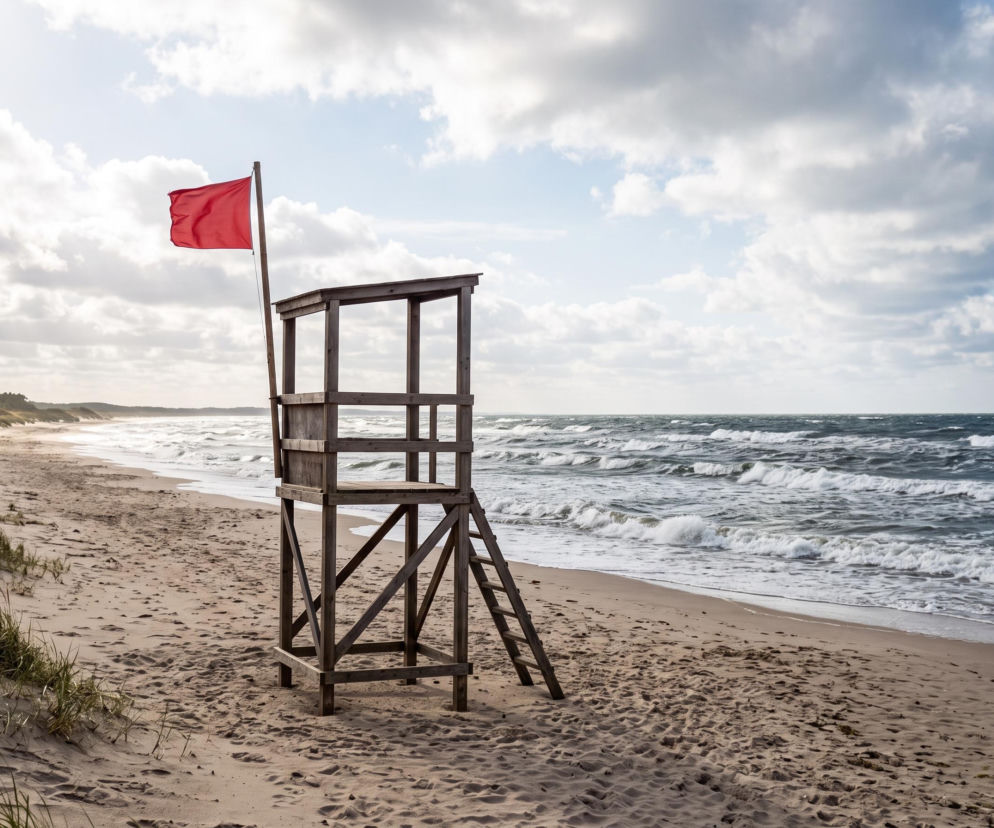 Czerwona flaga na wieży ratowniczej na pustej plaży w Gdyni. O zasadach kąpieli przeczytasz na Eska Trójmiasto.