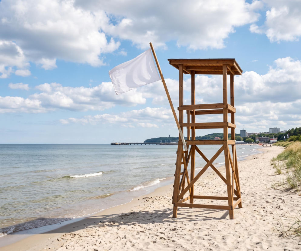 Drewniana wieża ratownicza z białą flagą na plaży w Gdyni. O bezpiecznych kąpielach przeczytasz na Eska Trójmiasto.