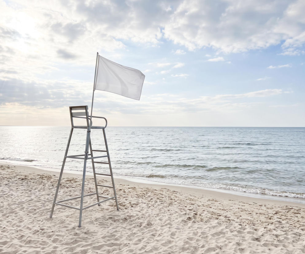 Biała flaga przy krześle ratownika na plaży w Grzybowie. O bezpieczeństwie nad wodą przeczytasz na SE Szczecin.