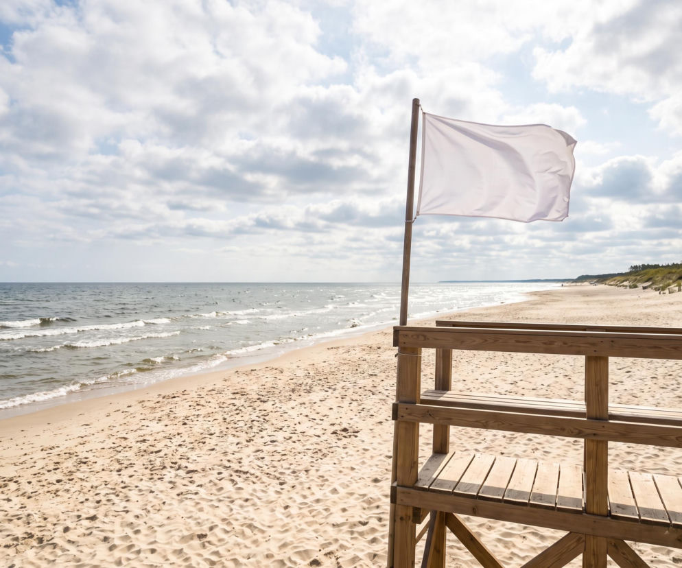 Biała flaga na wieży ratowniczej na pustej plaży w Grzybowie. O warunkach nad Bałtykiem przeczytasz na SE Szczecin.