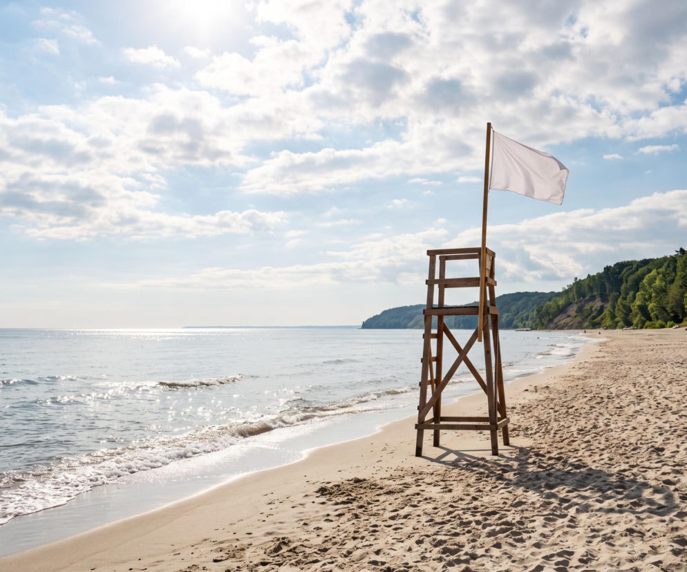 Wieża ratownicza z białą flagą na pustej plaży w Jastrzębiej Górze. O warunkach kąpieli przeczytasz w Eska Trójmiasto.