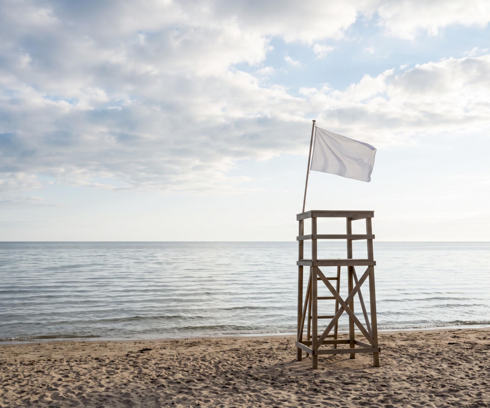 Biała flaga na wieży ratowniczej na pustej plaży w Jastrzębiej Górze. O warunkach kąpieli przeczytasz na Eska Trójmiasto.