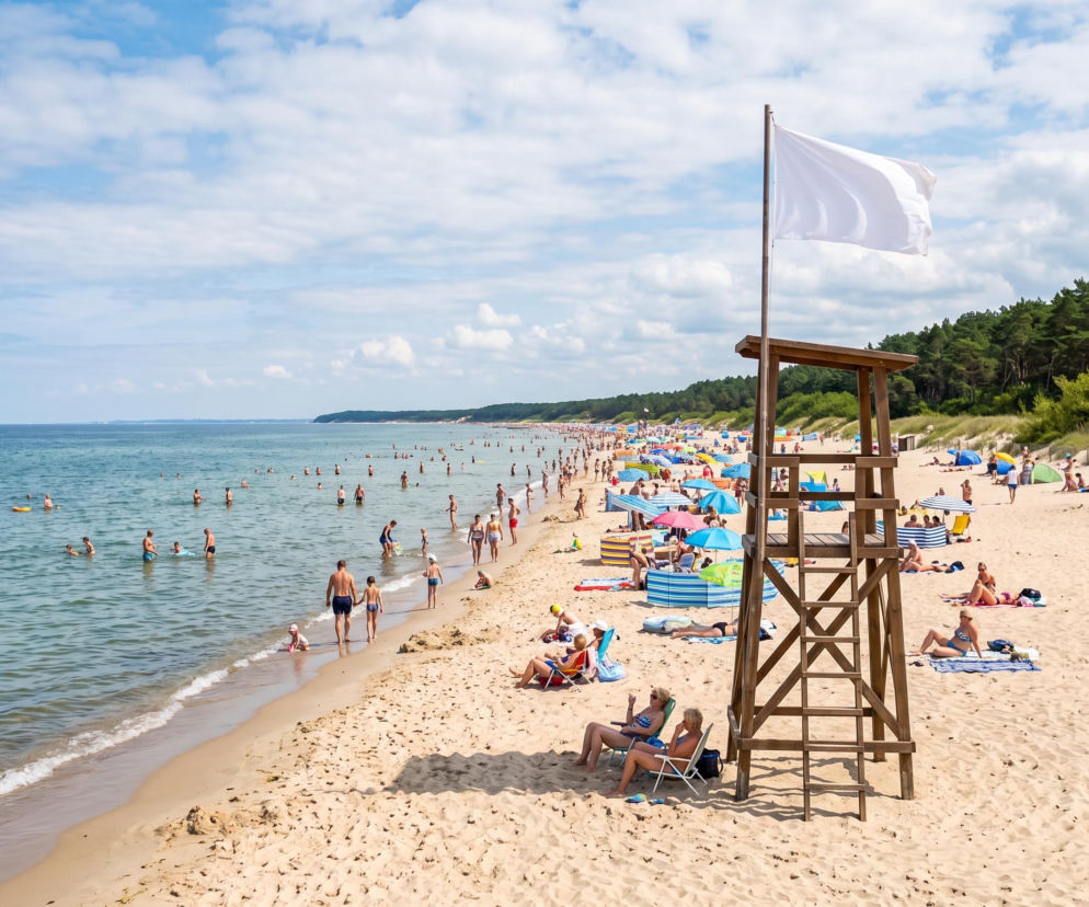 Biała flaga na wieży ratowniczej przy pełnej ludzi plaży w Krynicy Morskiej. O pogodzie przeczytasz na Eska Trójmiasto.