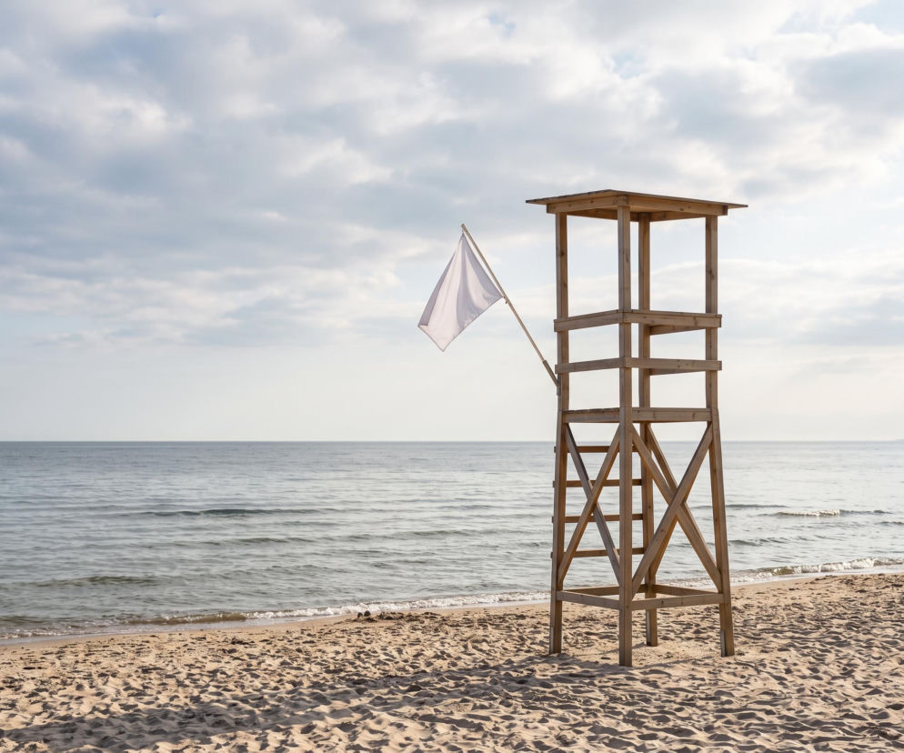 Drewniana wieża ratownicza z białą flagą na plaży w Mechelinkach. O warunkach nad morzem przeczytasz na Eska Trójmiasto.