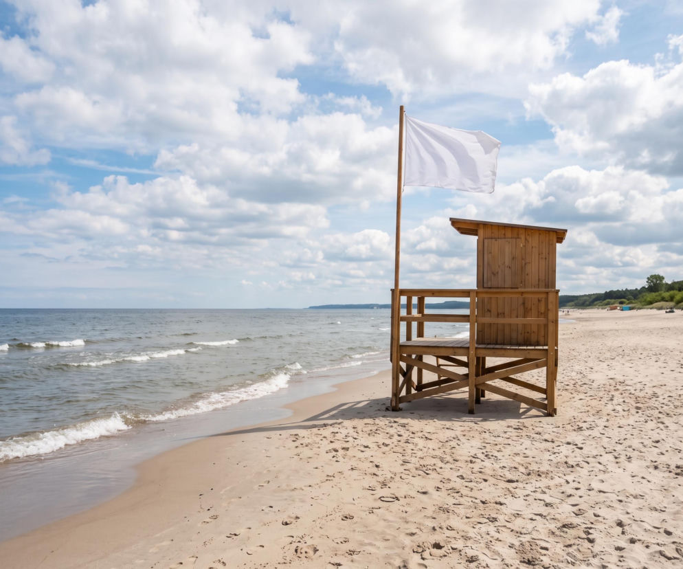 Biała flaga na wieży ratowniczej przy pustej plaży. O bezpieczeństwie kąpieli w Międzyzdrojach przeczytasz na SE Szczecin.