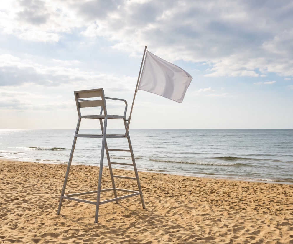 Biała flaga na wieży ratowniczej na pustej plaży w Mielnie. O bezpieczeństwie nad Bałtykiem przeczytasz na SE Szczecin.