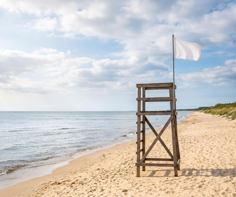 Drewniana wieża ratownika z białą flagą na pustej plaży w Mrzeżynie. O pogodzie nad morzem przeczytasz na SE Szczecin.