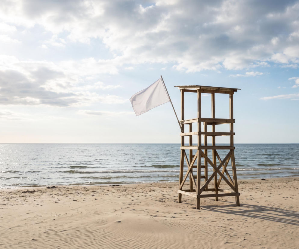 Drewniana wieża ratownika z białą flagą na plaży w Mrzeżynie. O braku sinic w morzu przeczytasz na SE Szczecin.