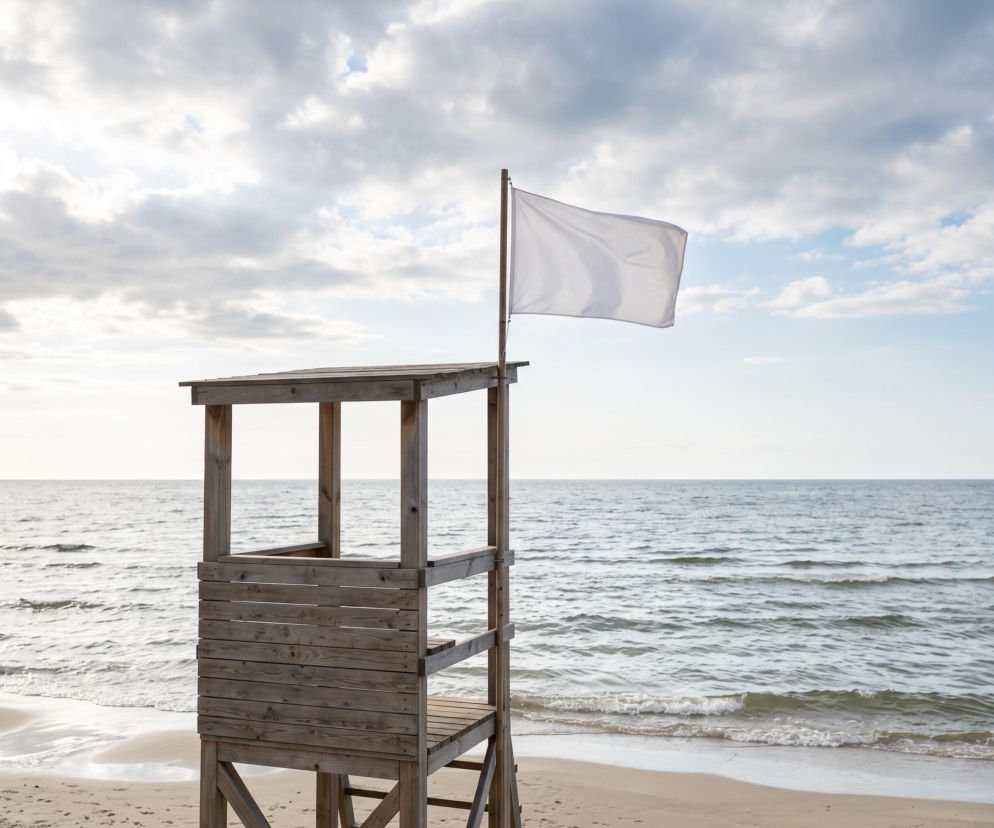 Drewniana wieża ratownika z białą flagą na plaży w Rewie. O czystości wody i braku sinic przeczytasz na Eska Trójmiasto.