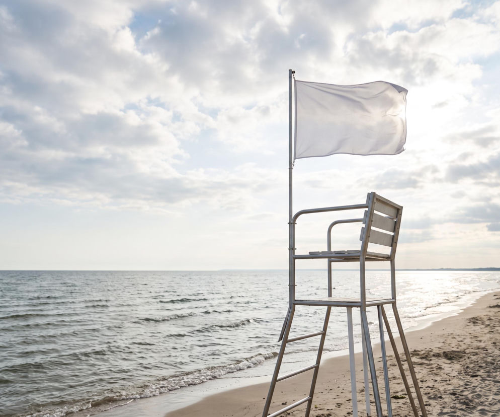 Biała flaga na wieży ratowniczej przy pustej plaży w Rowach. O bezpiecznej kąpieli przeczytasz na Eska Trójmiasto.