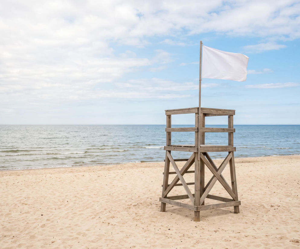 Drewniana wieża ratownika z białą flagą na piaszczystej plaży w Sarbinowie. O warunkach nad morzem pisze SE Szczecin.