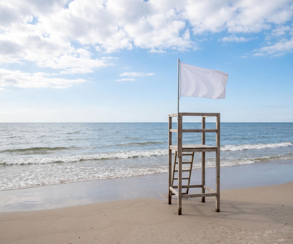 Drewniana wieża ratownicza z białą flagą na plaży w Sarbinowie. O bezpiecznej kąpieli przeczytasz na SE Szczecin.