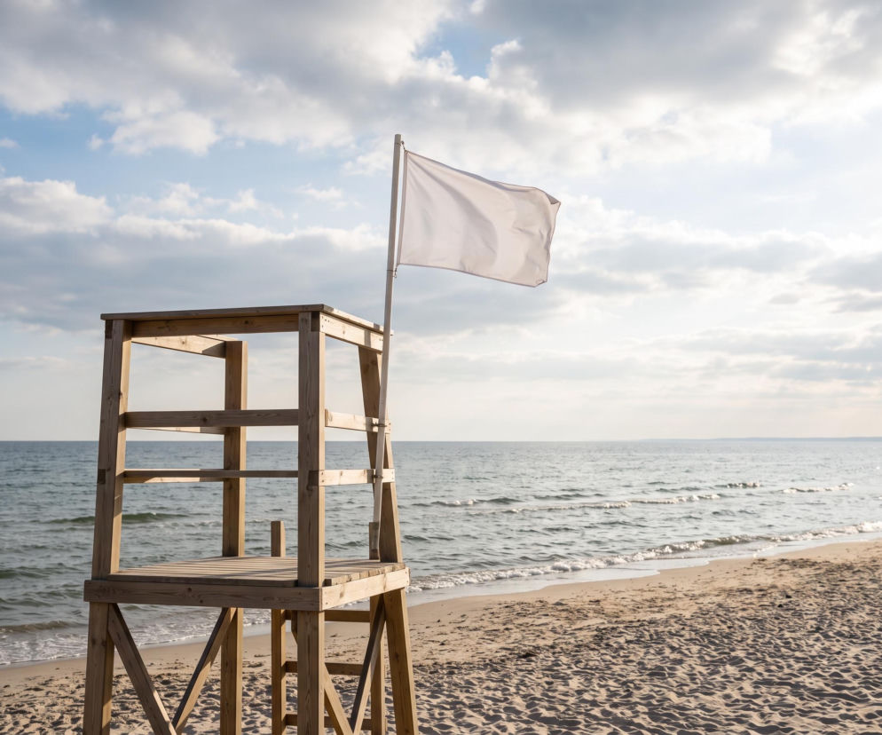 Drewniana wieża ratownika z białą flagą na plaży w Sarbinowie. O bezpieczeństwie nad wodą przeczytasz na SE Szczecin.