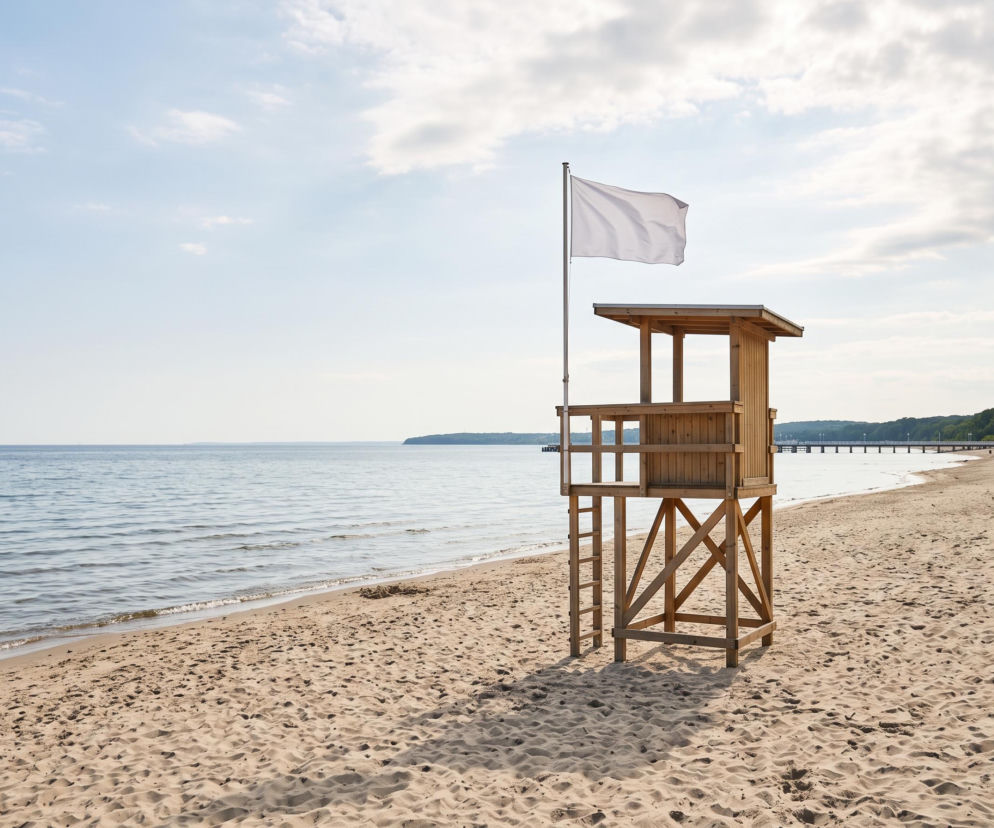 Drewniana wieża ratownicza z białą flagą na pustej plaży w Sopocie. O czystości wody przeczytasz na Eska Trójmiasto.