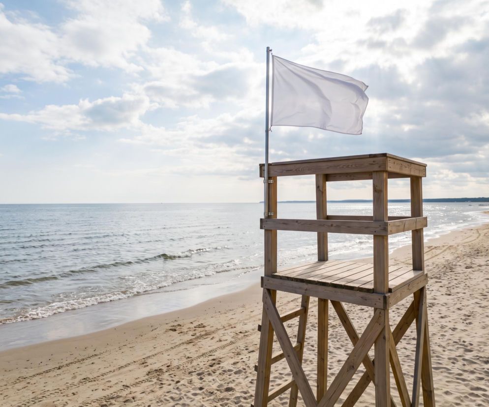 Drewniana wieża ratownicza na plaży z białą flagą. O czystości wody w Sopocie przeczytasz na Eska Trójmiasto.