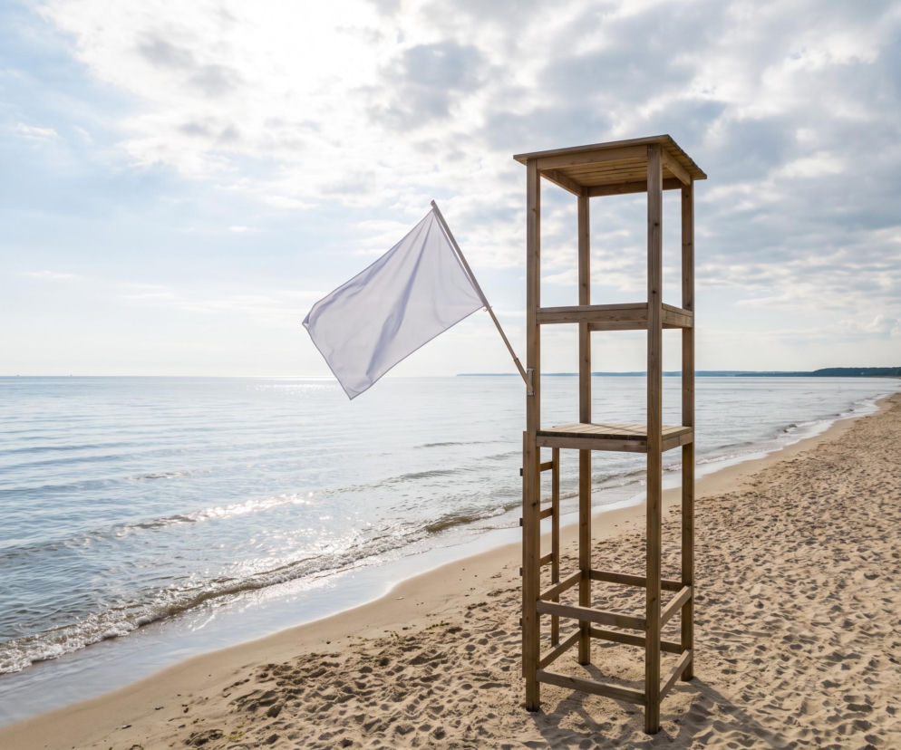 Drewniana wieża ratownicza z białą flagą na pustej plaży w Sopocie. O warunkach kąpieli przeczytasz na Eska Trójmiasto.